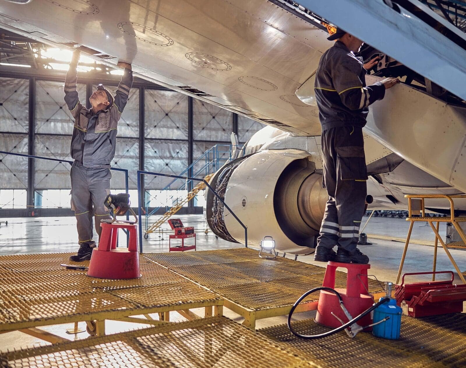 Deux ouvriers travaillent sous une aile d'avion.